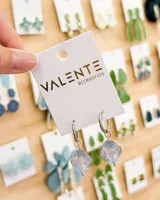 Aros de argolla pequeña en acero con dije colgante de cristal facetado en color azul traslúcido.