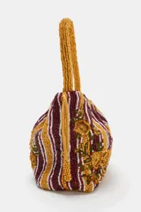 Bolso de hombro de tamaño mini, confeccionado con cuentas y abalorios que forman un diseño a rayas verticales y detalles de flores bordadas en tonos mostaza, bordó y blanco. Cuenta con asa corta de mano y cierre fruncido con cordones.