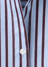 Camisa de corte recto con diseño de rayas, cuello camisero, manga larga con puños abotonados, bolsillo de parche en el pecho y cierre delantero con botones.