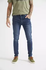 Jean de corte skinny para hombre, confeccionado en denim azul con efecto lavado. Presenta diseño clásico de cinco bolsillos, cierre frontal con botón y cremallera, y trabillas para cinturón.