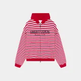 Campera con capucha de felpa de algodón, con diseño a rayas horizontales rojas y blancas, cierre frontal con cremallera bidireccional y bolsillos tipo canguro. Presenta grandes letras bordadas con el texto "EMESTUDIOS Madrid, 5135" en el pecho.