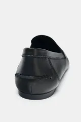 Mocasín de piel color negro con antifaz en la parte delantera y detalle de penny dorado. Tiene copete subido y punta redonda.