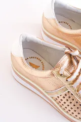Zapatillas acordonadas color dorado con capellada de cuero calado, base blanca y detalles en cuero blanco en el talón.