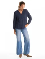 Blusa de algodón azul marino con bordado floral al tono. Presenta escote en V con terminación festoneada y mangas largas ligeramente abullonadas con puños abotonados. Su diseño es de silueta fluida y relajada.