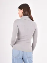 Polera de tejido de punto fino, con cuello alto doblado y mangas largas. Presenta un diseño ajustado al cuerpo con terminaciones acanaladas en puños y ruedo.