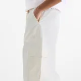Pantalón cargo New Balance de corte amplio y tiro medio, confeccionado en tela técnica ligera de color blanco. Presenta cintura elástica con cordón ajustable, bolsillos laterales tipo cargo y diseño de pierna recta.