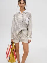 Short de corte boxy confeccionado en viscosa con estampado geométrico de estrellas en tonos rosados. Presenta una pretina elástica en color naranja y cordón de ajuste en color marrón.