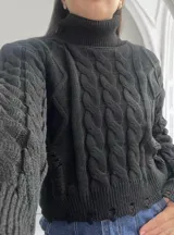 Sweater negro de punto con cuello alto y diseño de trenzas.