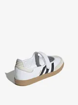 Zapatillas Adidas modelo Samba Jane, con diseño tipo Mary Jane. Presentan una capellada de cuero blanco con las icónicas tres tiras laterales en negro, puntera de gamuza en tono beige y suela de goma tipo gum. Incluyen una tira con cierre de velcro en el empeine.