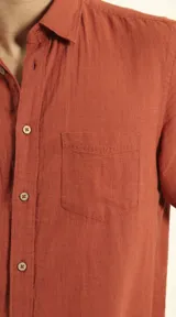 Camisa sport de manga corta, confeccionada en una mezcla de lino y algodón. Presenta cuello clásico, cierre frontal con botones de coco y un bolsillo aplicado en el pecho.