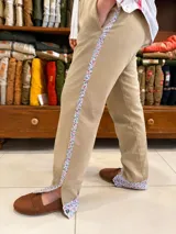 Bombacha de campo color beige, confeccionada en acrocel de algodón, de corte recto con bolsillos laterales. Presenta una franja lateral decorativa con estampado floreado y detalles a juego en los puños con aberturas en los tobillos.