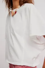 Remera de jersey de algodón blanca con silueta murciélago, escote barco y mangas dolman muy anchas de corte recto y holgado.