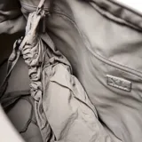 Bolso deportivo de gran capacidad con diseño arrugado, color gris claro. Cuenta con doble asa superior, correa ajustable y desmontable, y correas en la base para sujetar accesorios. Incluye compartimento principal con cierre, bolsillo frontal y bolsa interior desmontable.