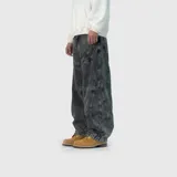 Pantalón jean de corte ultra baggy, color negro con efecto lavado ácido. Presenta costuras curvas decorativas en la parte superior y diseño de piernas amplias con ajuste en los tobillos.