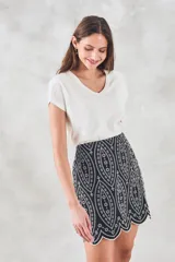 Minifalda negra con bordado blanco de motivos geométricos y terminación festoneada.