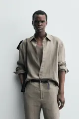 Camisa de manga larga color verde oliva, confeccionada en lino lavado con efecto ligeramente arrugado. Presenta cuello italiano y cierre frontal de botones.