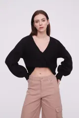 Sweater negro de tejido de punto con diseño cruzado en el frente, escote en V profundo y mangas largas con puños ajustados.