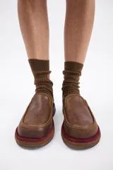 Zuecos de cuero vacuno en color beige, con diseño de punta redondeada y suela plana de goma.