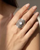 Anillo de plata 925 con diseño ovalado labrado y piedra de la luna central. Presenta detalles de relieve y texturas circulares en toda la superficie.