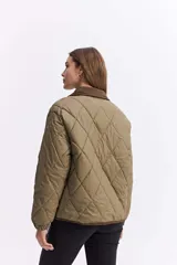 Campera matelaseada de diseño en rombos color verde oliva, con cuello y bordes en contraste color marrón. Presenta cierre frontal con botones a presión, mangas largas con puños elásticos y corte holgado.