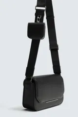 Bandolera negra con textura grabada, correa ajustable, monedero extraíble, compartimento principal con solapa imantada, bolsillo interno con cierre y bolsillo frontal con cierre.