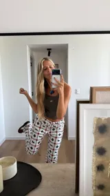 Pantalón de jean de corte recto con estampado integral de motivos geométricos y figuras de caballos en colores negro y naranja sobre fondo blanco.