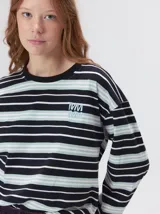 Remera de manga larga con diseño a rayas horizontales en tonos azul, blanco y negro. Presenta un cuello redondo al tono y un logo bordado en el pecho. El diseño destaca por tener un patrón de rayas diferente en las mangas y un calce holgado.