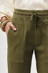 Pantalón tipo babucha de gabardina elastizada, color negro, con cintura elástica ajustable mediante cordón, puños en los tobillos, bolsillos diagonales frontales y bolsillos traseros con solapa y botón.