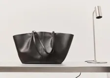 Bolso tipo shopper de efecto piel en color marrón oscuro, con diseño estructurado, doble asa de hombro y cierre de botón magnético.
