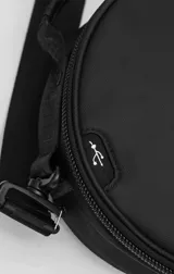 Bolso circular de estructura rígida, color negro, diseñado para el transporte de auriculares y accesorios. Cuenta con manija superior reforzada, correa de hombro ajustable con logo grabado, cierre perimetral y bolsillo trasero de acceso rápido.