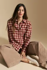 Camisa de estilo leñador con estampado de cuadros en tonos azul, negro y marrón. Presenta cuello clásico, cierre frontal con botones y mangas largas con puños abotonados.