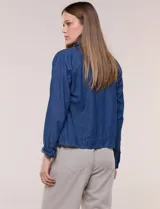 Campera de denim liviano azul, de corte clásico y silueta recta, con cuello camisero, cierre frontal con botones rústicos y bolsillos con solapa en el pecho.