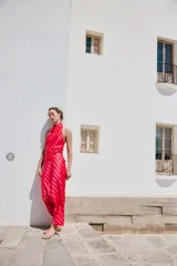 Falda midi fluida confeccionada en tejido satinado con estampado de rayas diagonales en tonos rojo y rosado, y cintura elástica.