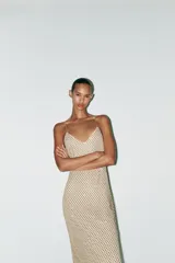 Vestido largo color dorado, confeccionado en tejido tipo red con aplicación de strass, escote pico y tirantes finos. Incluye forro interior y cierre en espalda con cremallera oculta en costura.