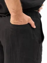 Short de lino con cintura elástica y cordón ajustable. Cuenta con dos bolsillos laterales y un bolsillo trasero, ofreciendo un ajuste cómodo y versátil.