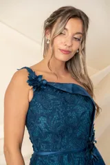 Vestido largo asimétrico de encaje color bordó, con un solo bretel y detalle de apliques florales en hombro y cintura. Presenta una pieza lateral de tafeta que cae desde el escote y un tajo pronunciado en el costado.