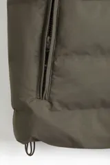 Chaleco acolchado color verde militar, con cuello alto, cierre frontal y bolsillos laterales con cierre.