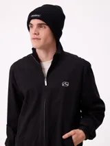 Gorro tipo beanie de punto acanalado en color beige, con parche rectangular negro con el logo de la marca en el frente.