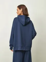 Buzo azul oscuro con capucha, corte oversize, manga larga y bolsillo canguro frontal.