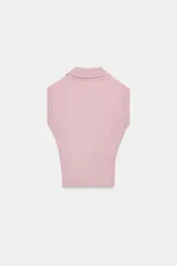 Chaleco de punto color blanco, estilo polo, sin mangas (manga sisa) y cuello solapa. La parte inferior termina en rib.