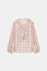 Blusa de manga larga abullonada con puños elásticos, cuello redondo con volantes y detalle de cordón ajustable en el escote pico. Presenta un estampado a cuadros en tonos blanco y rosado/marrón claro.