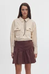 Falda corta de algodón color negro, con volados, cartera de botones frontal y diseño de tiro alto con corte curvo en la cintura.