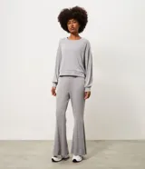 Pantalón deportivo femenino Get Over de corte flare, confeccionado en microfibra de color gris. Presenta cintura con pretina fija, diseño acampanado desde la rodilla y costuras decorativas frontales.