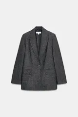 Blazer de corte sastrero confeccionado en tejido de lana con diseño de espiga. Presenta cuello con solapas, hombreras, cierre frontal con un botón y bolsillos delanteros con solapa.