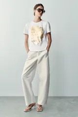 Camiseta blanca de manga corta y cuello redondo, con detalle de estampa central metalizada de efecto texturizado y diseño regular fit.