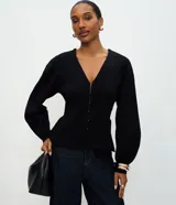 Cardigan de punto negro con escote en V, cierre frontal mediante ganchos metálicos y mangas largas con puños ajustados. Presenta un diseño entallado en la cintura con mangas ligeramente abullonadas.