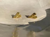 Par de aros dorados con forma de corazón irregular.