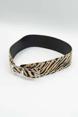 Cinturón de cuero con estampado animal print de cebra, decorado con tachas metálicas plateadas a lo largo de los bordes y hebilla metálica plateada.
