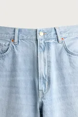 Jeans de denim de algodón en color azul con efecto desgastado, tiro medio y corte recto de ajuste holgado (loose fit). Cuenta con diseño clásico de cinco bolsillos y cierre frontal con cremallera y botón.