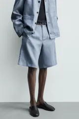 Bermuda relaxed fit confeccionada en lino color celeste, con bolsillos laterales, bolsillos traseros de vivo y cierre frontal con cremallera y botón.